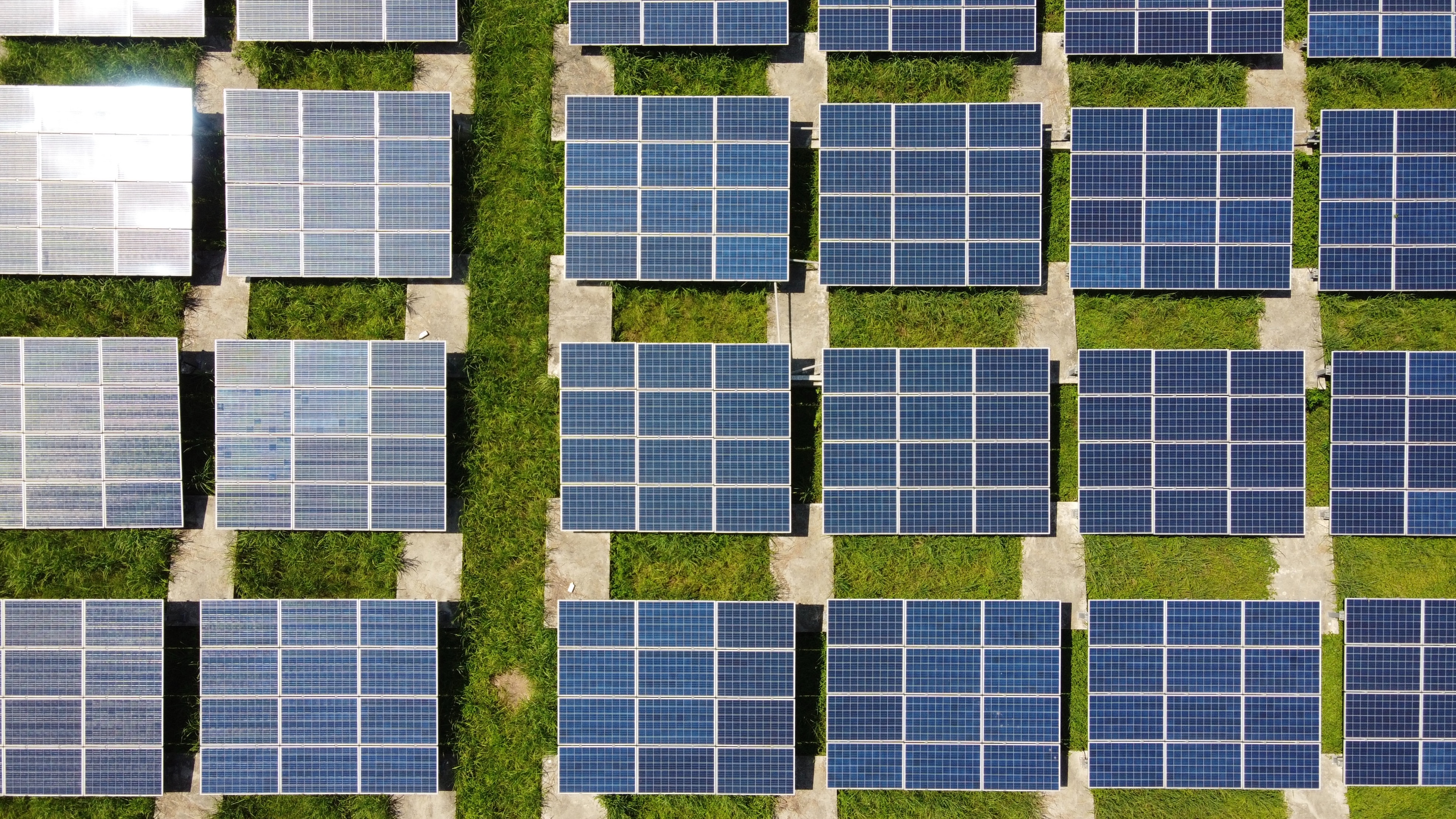 Redirection: Uma foto do alto apontada para o chão mostrando diversas placas solares sobre a grama